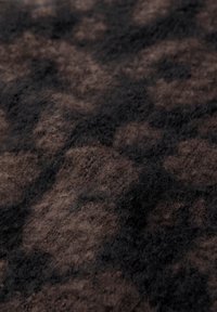Tissu en laine douce dans des nuances de marron et de noir, présentant une texture duveteuse avec des motifs abstraits créant une apparence superposée.