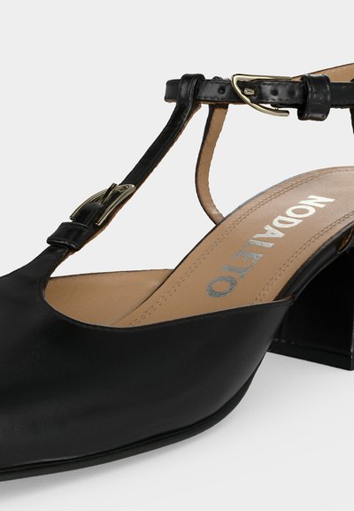 Μαύρο δερμάτινο γυναικείο πέδιλο με τακούνι, T-λαιμόκοψη και χρυσή πόρπη, τετράγωνη μύτη και ορατή εσωτερική σόλα με το λογότυπο "NODALETO".