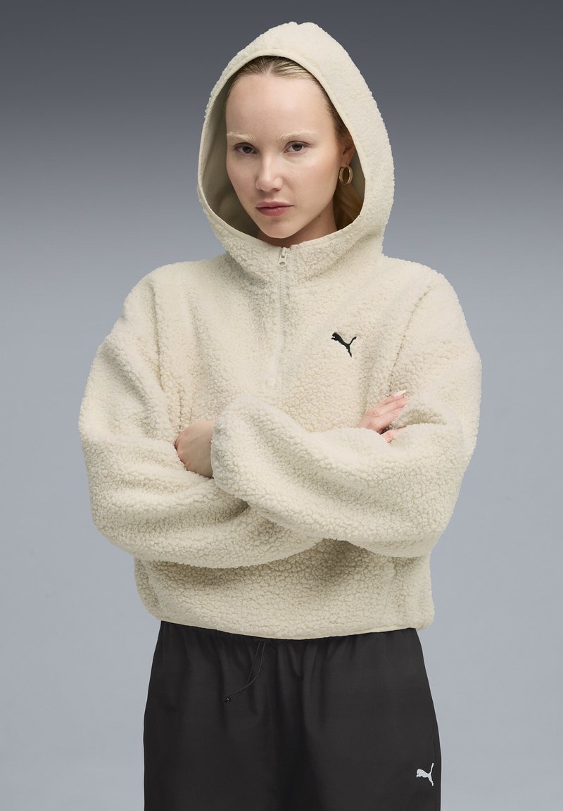Beiger Fleece-Pullover mit Kapuze, Reißverschluss und Logo. Aus dicken, strukturierten Stoff gefertigt und mit lockeren Ärmeln für mehr Komfort.