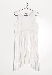 Valkoinen hihaton mekko, jossa on teksturoidut sivupaneelit, rypistetty vyötärö ja röyhelöhelma. Saumaton kangas, rento leikkaus ja pyöreä pääntie.