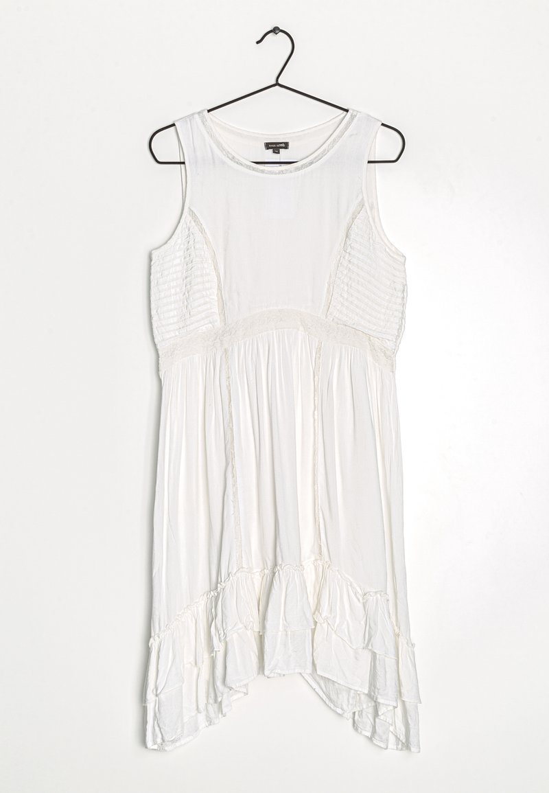 Valkoinen hihaton mekko, jossa on teksturoidut sivupaneelit, rypistetty vyötärö ja röyhelöhelma. Saumaton kangas, rento leikkaus ja pyöreä pääntie.