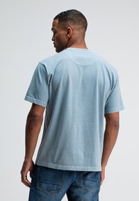 Lichtblauw katoenen T-shirt met een ronde halslijn. Korte mouwen en een ontspannen pasvorm. Rechte zoom en minimale stikseldetails.