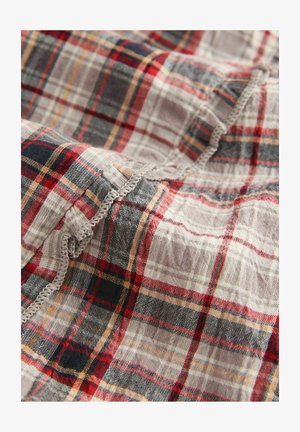 Tissu à carreaux dans des tons rouge, marine et beige, texture légère avec des bords bruts et une finition légèrement effilochée, motif tissé complexe.