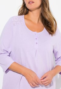 Levandulový top s dlouhým rukávem, kulatým výstřihem, řadou knoflíků, krajkovými detaily na ramenou a mírným nařasením pro uvolněný střih.