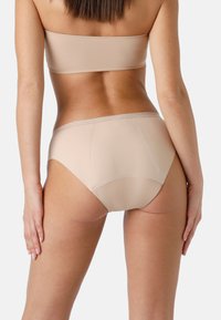 Mutandine bikini beige senza cuciture con morbido elastico in vita, texture liscia e design a copertura totale, caratterizzate da un'apertura alta per le gambe.