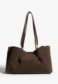 Pruun nubukist kott sileda nahkaga sangadega, millel on struktureeritud kuju ja minimalistlik disain, millele on lisatud pealmine õmblus.