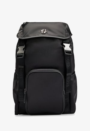 Black nylon backpack with a top flap, front zipper pocket, and adjustable straps. Features silver hardware and a textured logo accent.