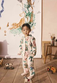 Kaheosaline pidžaamakomplekt pehmest kreemivärvi kangast, millel on värvilised looma- ja lillemustrid. Püksid ja särk on varustatud nuppudega ning kraega.