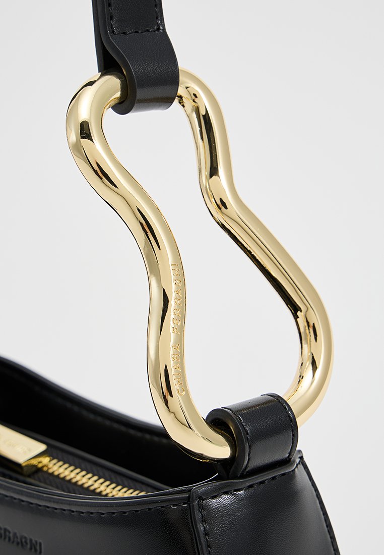 Schwarze Lederhandtasche mit einem markanten goldfarbenen gedrehten Hardware und einer glatten Oberfläche. Reißverschlussdetails und geprägtes Logo vorhanden.