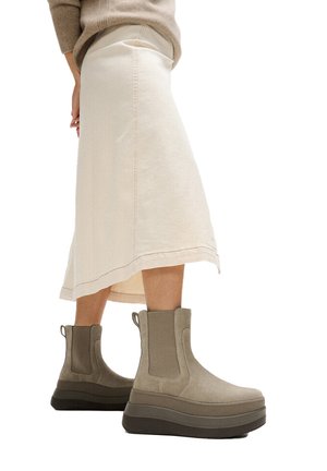 Beige plateau enkellaarsjes van zacht stof met elastische zijkanten en een gestructureerde matte afwerking, gecombineerd met een licht crèmekleurige rok.