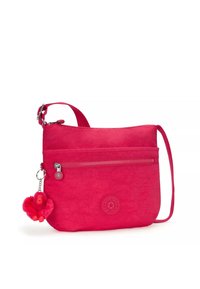 Piccola borsa a tracolla in tessuto rosa brillante, con una tasca frontale con zip, tracolla regolabile e un charm a forma di scimmia pelosa attaccato.