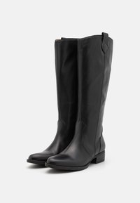 Schwarze, knielange Stiefel aus Leder mit glatter Oberfläche, leichtem Absatz und gebogener Nahtdetails im oberen Bereich. Mit einer Ziehschlaufe auf der Rückseite.