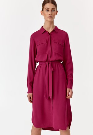 Fuksia paita-mekko, joka on valmistettu kevyestä kankaasta, sisältää napitettavan etuosan, kaksi rintataskua, vyötärövyön ja pitkät hihat.