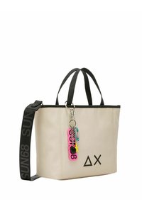 Borsa a tracolla beige con manici neri, tracolla regolabile, dotata di zip in cima, stampa del logo e un colorato portachiavi charm attaccato.