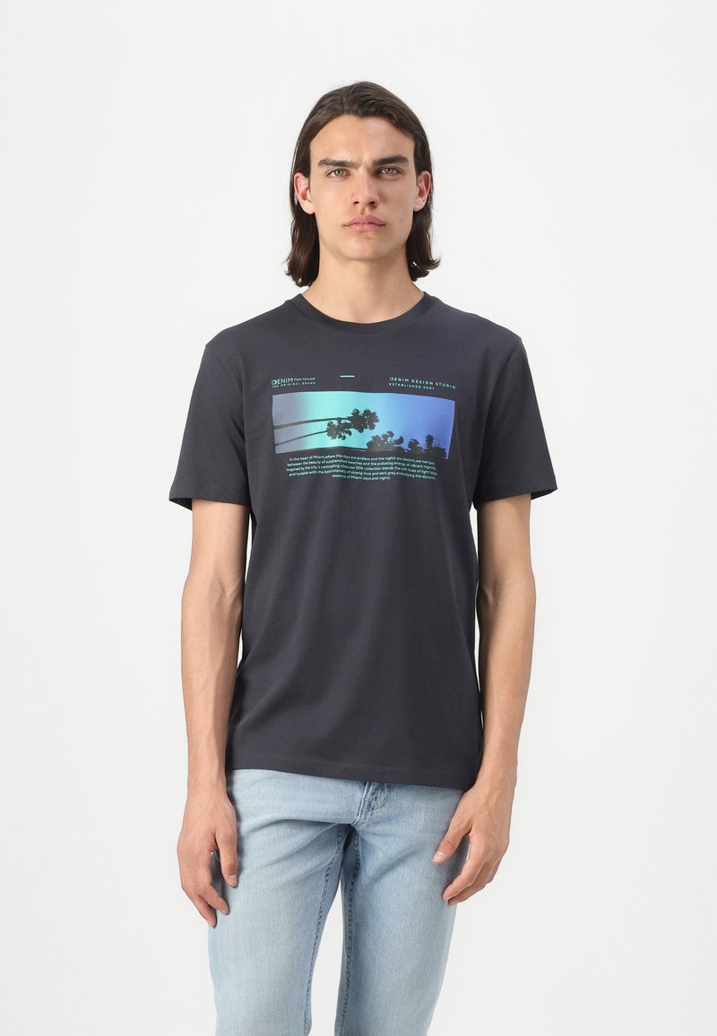 Mørkegrå bomulls-t-skjorte med et rektangulært grafisk design med palmer og tekst i blå og grønne nyanser på forsiden. Kortermet.