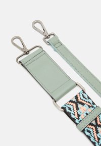 Correa de bolso ajustable con clips de metal plateado, detalles de cuero verde pálido y un patrón geométrico tejido en negro, azul y durazno.