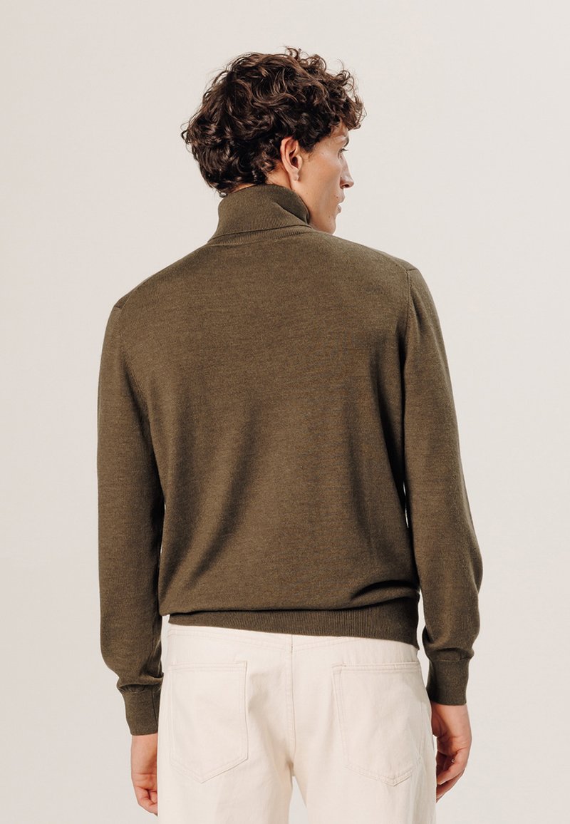 Pull vert en tricot avec un col montant, doté de manches longues et d'une taille ajustée. La texture semble douce et légère.