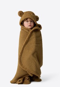 Pruun fliisist tekk karuteemalise kapuutsiga, millel on ümardatud kõrvad ja tekstuuriga pind, mis mähib lapse keha.