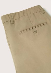 Vue arrière d'un pantalon beige avec passants de ceinture, une poche passepoilée boutonnée unique et une texture de tissu lisse.