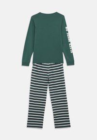 Dark green long-sleeve top with white text on sleeve paired with green, navy, and white horizontal striped pants pajamas.