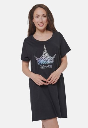 Woman smiling, wearing black Disney 100 t-shirt dress with a large crown graphic and "100 Years of Wonder" text on front.
