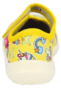Gelbe Kinderschuhe mit einem Obermaterial aus Stoff, das mit Einhorn-, Regenbogen- und Sternmustern verziert ist. Mit Klettverschluss für einfaches An- und Ausziehen. Weiße Laufsohle.