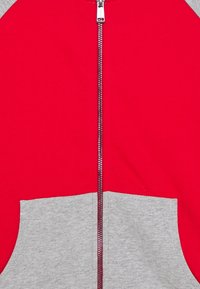 Rode zip-up hoodie met grijze onderpanelen en zakken. Glad stof met een rits en hoge hals, met een kleurcontrast.