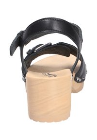 Schwarze Leder-Sandale mit massivem Holzabsatz, verstellbarem Riemen und silbernem Schnallendetail. Texturiertes Fußbett für Halt und Komfort.