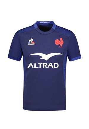 Maillot de sport bleu foncé à manches courtes, avec un logo de poulet rouge et une marque d'entreprise blanche. Fabriqué en tissu léger et texturé.