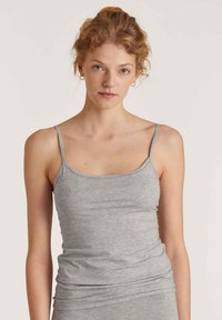 Grijze tanktop met dunne bandjes, gemaakt van zacht, lichtgewicht materiaal. Heeft een strakke pasvorm en minimale naden voor comfort.