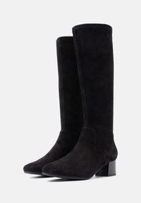 Sorte semskede knelange støvler med spiss tå og blokkhelt. Glatt tekstur med subtile sømdetaljer ved ankelen og toppen.