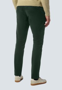 Groene chino's van katoen met een slim fit, voorzien van twee achterzakken en opgerolde zoom, gecombineerd met lichte sneakers.