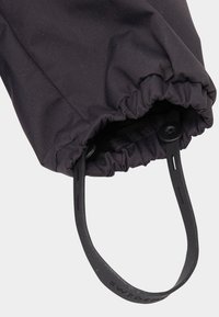 Black fabric cuff with gathered elastic opening, featuring an adjustable black strap with a snap button for secure fit.