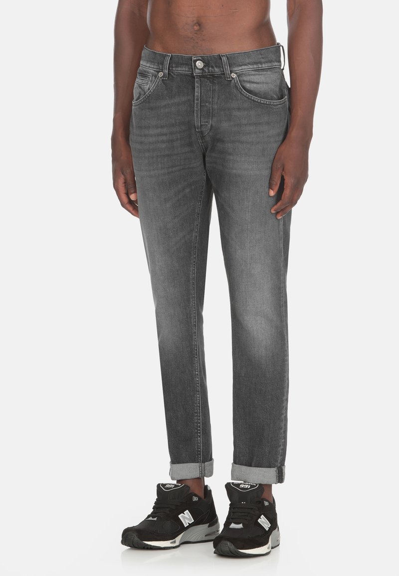 Jeans in denim grigio scuro con una vestibilità comoda, cuciture in vista, cinque tasche e polsini arrotolati, abbinati a sneakers nere.