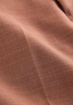 Tessuto testurizzato di un rosa tenue, che mostra un primo piano di fili intrecciati e una superficie liscia, evidenziando la sua fine trama.