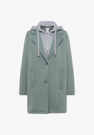 Manteau vert boutonné avec un sweat à capuche gris zippé en dessous, doté de cordons de serrage et de deux poches avant.