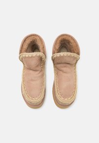 Scarpe slip-on in suede color sabbia con una morbida fodera in pelliccia, rifiniture decorative intrecciate e una suola in gomma flessibile. Design arrotondato e casual.