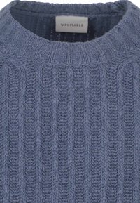 Donkerblauwe gebreide trui met een geribbelde textuur en een ronde halslijn. Het label leest 'SUITABLE' en bevindt zich aan de binnenkant van de kraag.