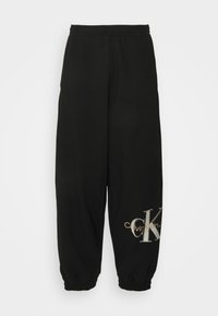 Svarta joggerbyxor tillverkade av mjukt tyg, med resårmidja och muddar. Prydda med en stor metallisk "CK"-logotyp i silver och guld.