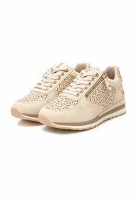 Zapatillas beige hechas de material perforado que cuentan con un zipper decorativo, cordones redondos y una suela texturizada con un ligero plataforma.