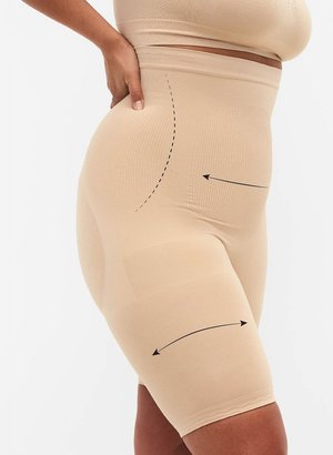 Nahaufnahme einer Person, die beige Shapewear-Shorts trägt, mit Pfeilen, die Kompressionszonen am Bauch, an der Hüfte und an den Oberschenkeln anzeigen.