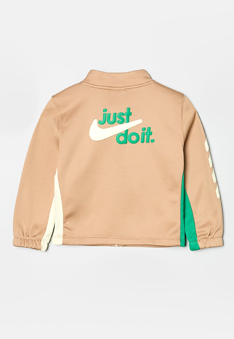 Jasnobrązowa polarowa kurtka z zielonymi i kremowymi akcentami, z logo "just do it" na plecach i elastycznymi mankietami.