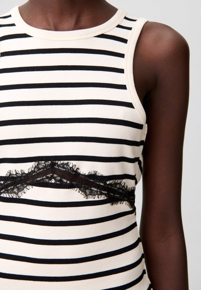 Top senza maniche a righe bianche e nere con scollo rotondo, caratterizzato da un accento in pizzo nero trasparente lungo la parte centrale. Materiale in misto cotone.