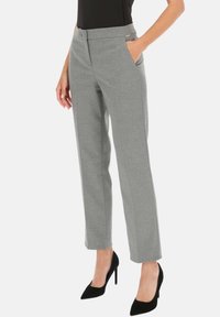 Szare spodnie o dopasowanym kroju z prostym fasonem, z bocznymi kieszeniami i subtelnymi metalowymi akcentami. Gładka tekstura, w połączeniu z czarnymi szpilkami.