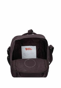 Borsa viola scuro con chiusura con zip. L'interno include un'etichetta con il nome e una tasca. Presenta una maniglia superiore e una tracolla regolabile. Tessuto resistente.