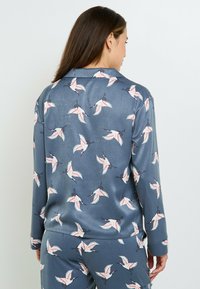Set di pigiama in seta blu scuro con motivi di gru bianchi e rosa. Presenta un colletto classico e maniche lunghe con una vestibilità comoda.