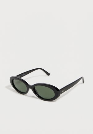 Black oval Ray-Ban sunglasses with green tinted lenses and slender arms, placed angled on a white surface.