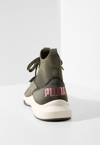 Green and gray athletic shoe with a textured upper, featuring a prominent pink "PUMA" logo on the heel and gray laces.