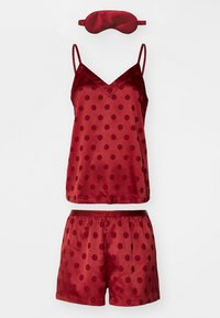 Set de pijama din satin roșu, care include o bluză cu decolteu în V și puncte, pantaloni scurți asortați cu talie elastică și o mască de somn coordonată.