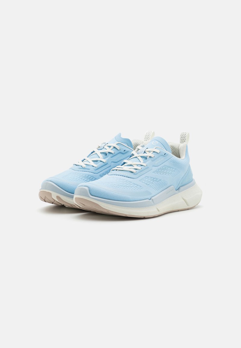 Helleblaue Sportschuhe mit einem strukturierten Mesh-Obermaterial, gepolsterter Sohle, weißen Schnürsenkeln und einer kleinen Zuglasche an der Ferse.